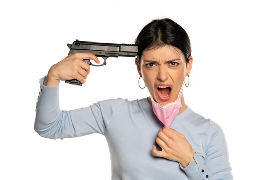Woman with a gun pulling her face mask, isolated on white.