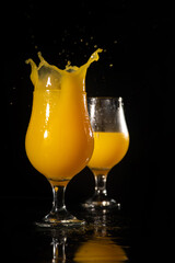 Naklejka na ściany i meble Orange juice, splash in beautiful glasses of orange juice, black background, selective focus.
