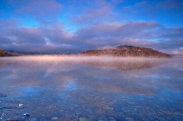 湖面に朝靄の漂う早朝の湖。氷点下の朝の屈斜路湖。阿寒摩周国立公園。北海道、日本。