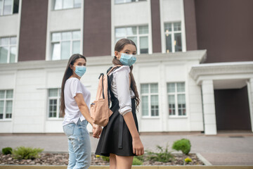 Mom and daughter in protective masks going to school