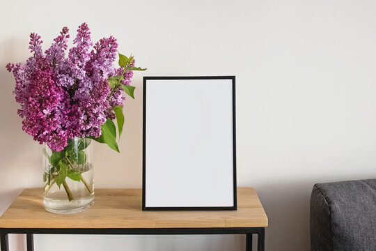 Empty frame and bouquet of purple lilac in a vase