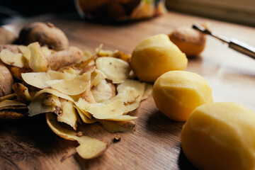 Three russet potatoes peeled and ready for cooking, with leftover peels on the table by the window