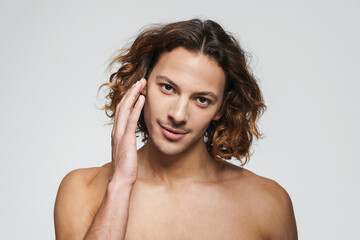 Obraz premium Pleased shirtless guy posing and touching his face