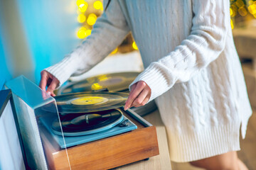 Woman in white clothes putting a record on