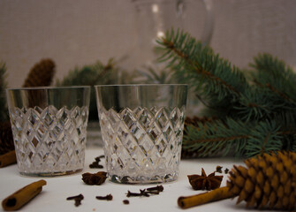 Crystal utensils on a white background next to lie spices cinnamon, cloves, anise, badyan for mulled wine and spruce branches in the background