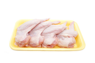 Raw Chicken wings in a yellow polystyrene container isolated on white background. Four fresh...