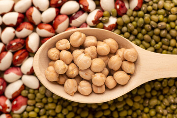 Raw chickpea in wood spoon on beans and lentil background,close up. Protein for vegetarian concept