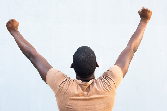 portrait young black man with arms raised and fist pump