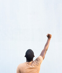 behind young black man with arm raised and fist pump in the air