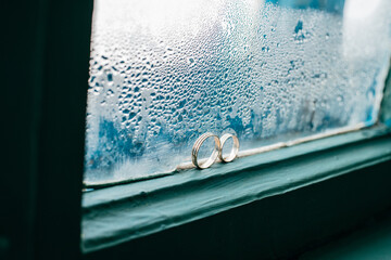 two gold wedding rings on the background of a frosty blue window