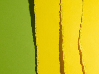 torn edges of yellow cardboard on a green background
