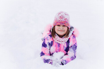 Fototapeta na wymiar Little happy cheerful girl playing outdoors in winter snow park