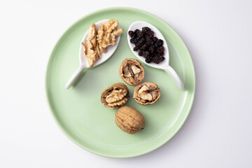 walnuts and raisins lie on a green plate