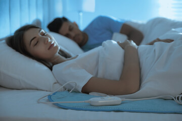 Couple sleeping on electric heating pad in bed at night © New Africa