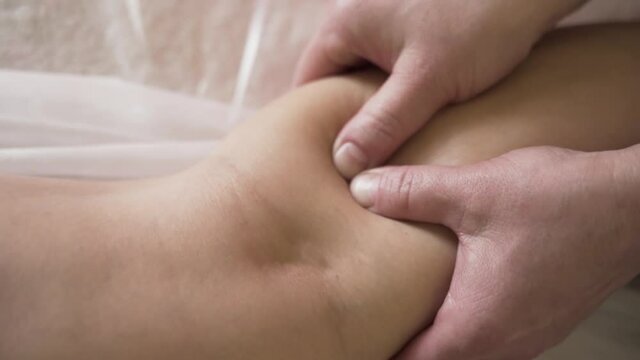 Close up of professional legs massage in the spa salon by sensitive female hand. Action. Premium massage to a female client, working with trigger points.