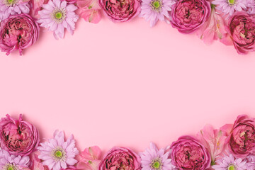 Frame made of rose and aster flower texture on a pink background with copyspace. Festive composition.