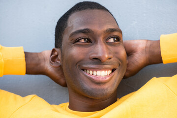 Close up smiling young African American man  with hands behind head