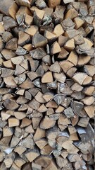 Woodpile. Wall firewood. Background from dry chopped logs in a heap. A wall of firewood, a background of dry chopped firewood. Alternative fuel concept. A snapshot of the natural background.