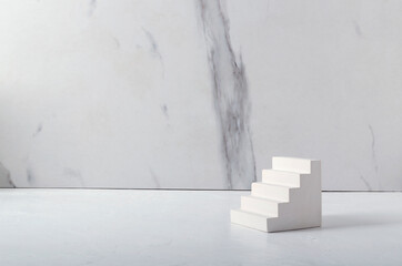 Bright stone stairs on the white desk against marble wall.Empty space
