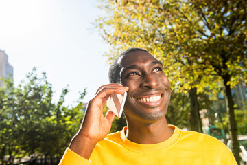 Close up happy young African American man talking on cellphone outside