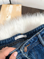 White blank label on the belt of blue jeans close up on wooden background