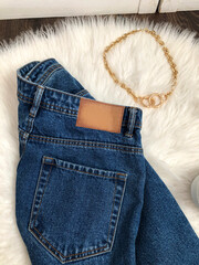 Leather blank brown label on the belt of blue jeans close up on fur background