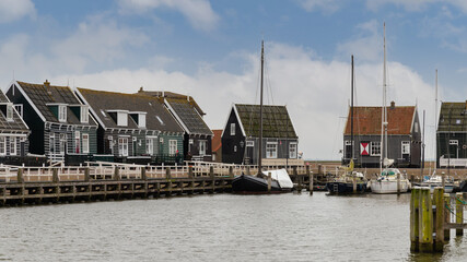 Fototapeta na wymiar Traditional wooden houses on the quay of the small harbor of the picturesque fishing village on the former island of Marken in the Netherlands 