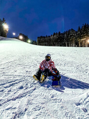 Fototapeta na wymiar Ski base, resort. Young woman with snowboard in helmet rides from the mountain