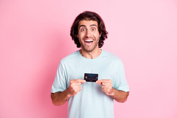 Portrait of impressed funky guy hold card wear blue outfit isolated on pastel pink color background