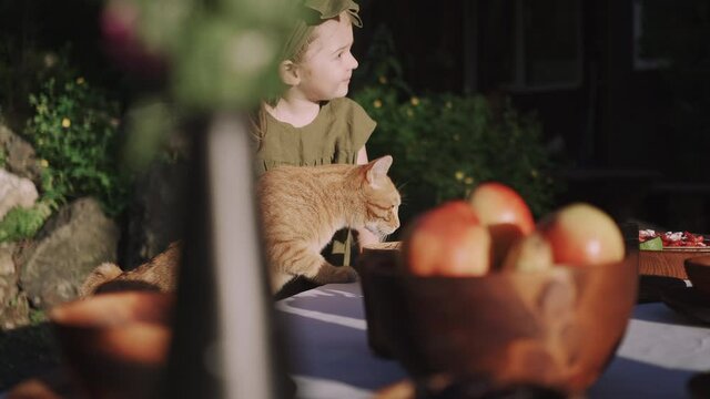A girl with a ginger cat Kurilian bobtail sitting at the table