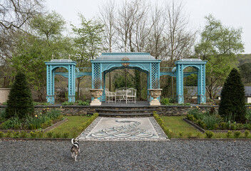 Fototapeta premium A beautiful antique decorative victorian style metal summer house awning in a green flower garden in an english countryside. Traditional victorian england architecture.