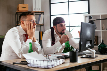 Two friends drinking beer in office. Colleagues are celebrating a big accomplishment at work..