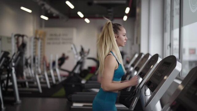Young fitness girl running on treadmill machine.