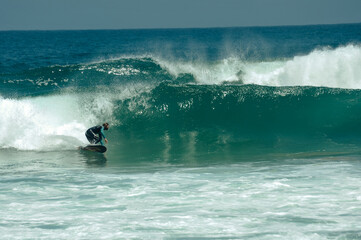 A man surfing  green wave of his height, doing a bottom turn