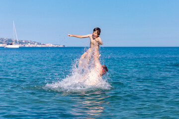 A man with his son swimming and playing in the sea.  A father throws a boy over the water. Family having fun in water