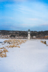 Lighthouse on a winter day on a frozen snow-covered river. Beautiful winter landscape