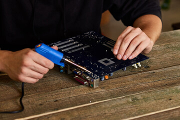 Engineer or technician repair electronic circuit board with soldering iron.