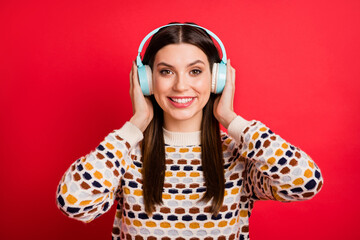 Photo portrait of cheerful girl wearing blue earphones wireless listening music isolated vibrant red color background