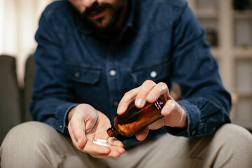 Young man drink medicine pill. Close up of man holding pill..