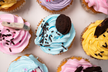 Delicious homemade cupcakes with Colorful cream and topping with candy and Chocolate Cookies. Homemade autumn holiday dessert