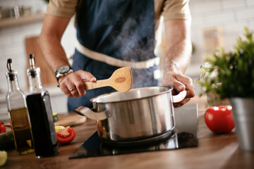 Young man cooking lunch at home. Handsome man preparing delicious food.