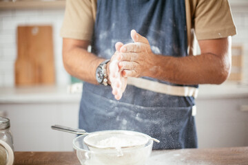 Attractive man cooking in modern kitchen. Handsome man playing with flour while preparing delicious food.