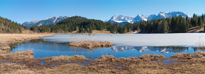 tranquil lake Geroldsee with ice cover and reflecting montain range at early springtime, Karwendel alps bavaria
