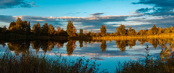 Fototapeta premium High resolution stitched panorama of a beautiful summer sunset with reflections in a pond near Aholming, Bavaria, Germany