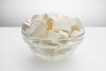 Feta cheese closeup cut into cubes in a transparent bowl, close up