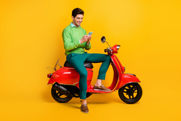 Obraz na płótnie Canvas Full length profile photo of handsome guy sit on moped blog user wear sweater isolated on yellow color background