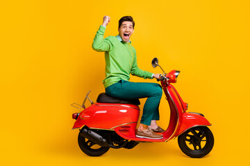 Fototapeta na wymiar Full body profile photo of delighted guy fist up open mouth shout yeah sit in bike isolate don yellow color background