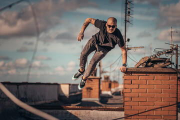 Urban young man jumping and doing parkour on top of the building  - Powered by Adobe