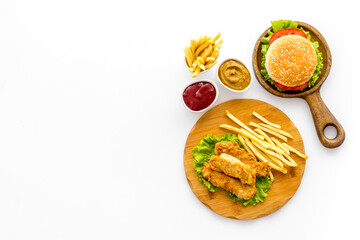 Burger with fried potatoes and chicken, top view