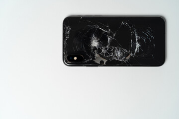 Closeup of black smartphone with broken back glass on white background. A close up picture of mobile phone ready for repair